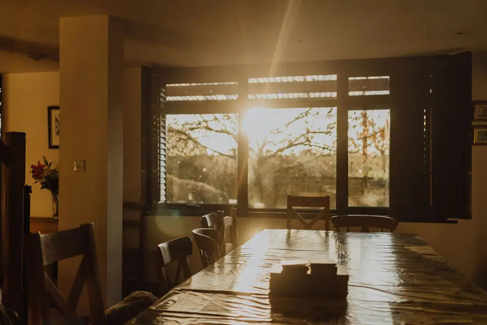 Morning light falling across an empty dining table, the room quiet before anyone is up.